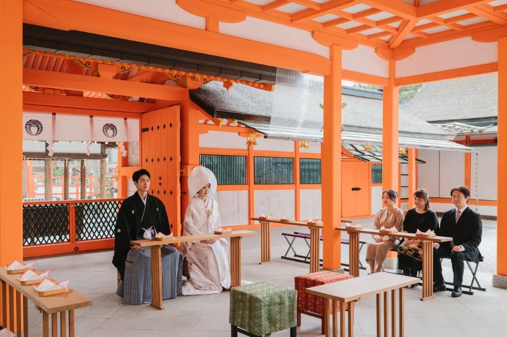 家族数名に見守られる少人数の神社挙式、または新郎新婦の自然な笑顔